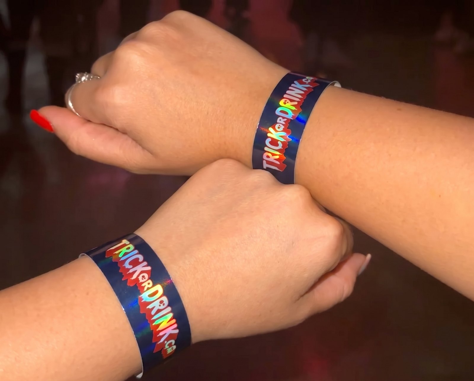 Two Trick or Drink wristbands on wrists inside a Toronto club